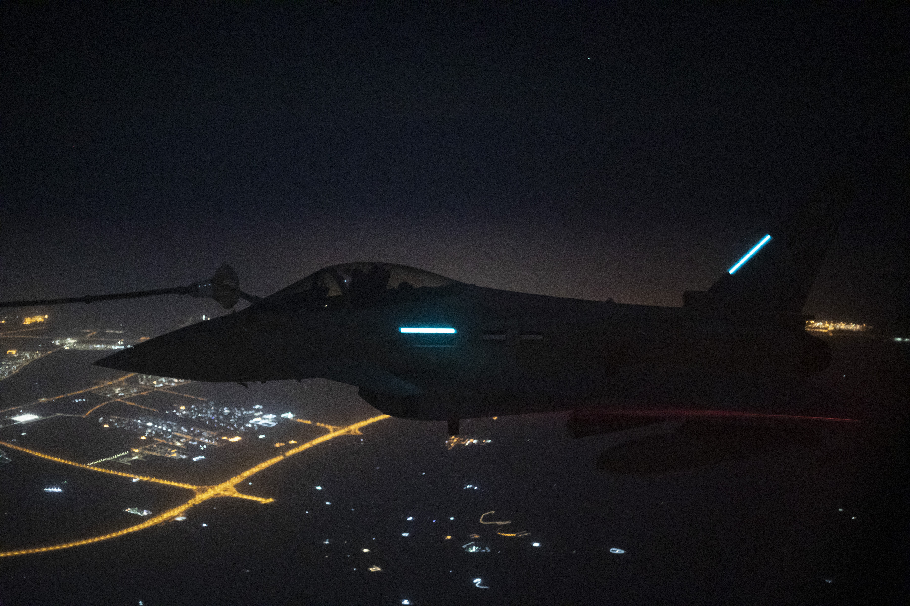 Image shows RAF Typhoon flying over Qatar during air to air refuelling exercise at nighttime.